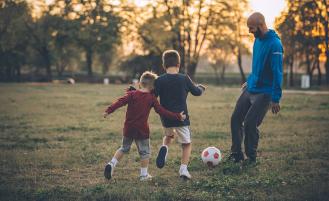 two-boys-playing-soccer-with-adult