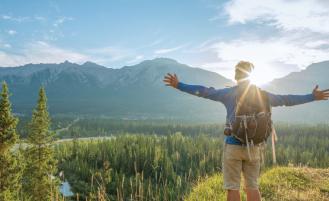 hiker-extending-arms-viewing-mountain-and-tree-view