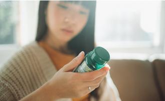 Hand-holding-bottle-containing-dietary-supplements