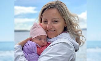 Agota holding her baby on a beach.