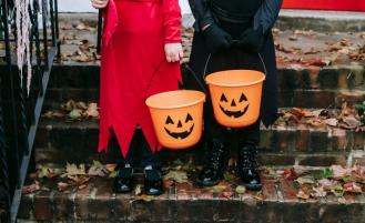 Children in costumes hold jack-o'-lantern buckets. 