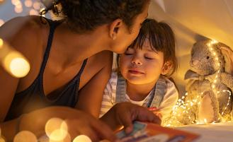 Parent kisses child on forehead before sleep.