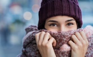 Woman holding scarf up over face.