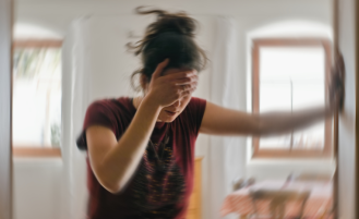 Person with hand against wall and appearing dizzy.