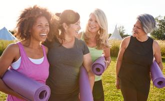 Women with yoga mats talking outside.