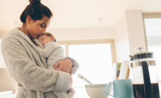 Woman in bathrobe holds newborn.