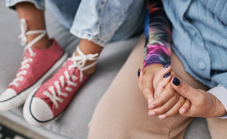 Teen sitting on couch and holding parent's hand.