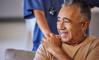 Older man holds the hand of a nurse.