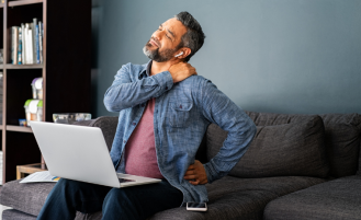 Man using laptop holds neck in pain.