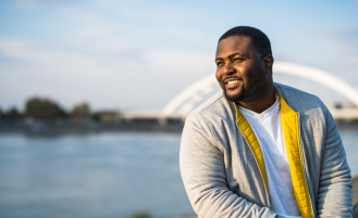 Man sitting by water looks off into the distance.