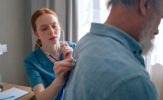 Nurse listens to man's lungs.