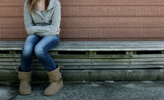 Young girl sits alone on bench.