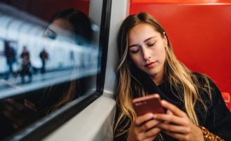 Girl on subway looks at phone.