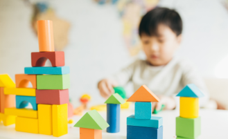 Toy building blocks sit on table with child in the background.