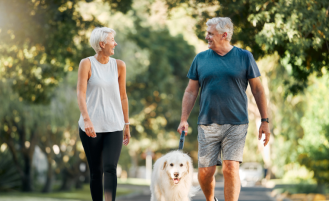 Couple walks outside with dog.