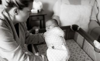 Mother placing baby in crib