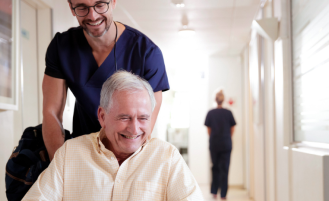 Nurse pushes patient in wheelchair.