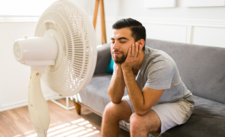 Man cools off in front of fan.