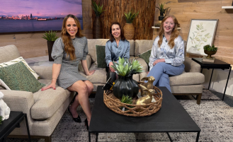 On the New Day NW set, host Kelly Hanson sits with Dr. Pam Paley and Rachel Owen for an interview about gynecological cancer. The three are seated on a brightly lit studio stage.