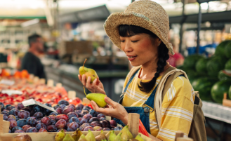 Woman looks at fruit at farmers market stall