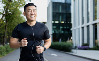 Asian smiling young man doing a morning jog in the city wearing headphones