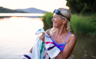  Portrait of active senior woman swimmer drying herself with towel outdoors by lake