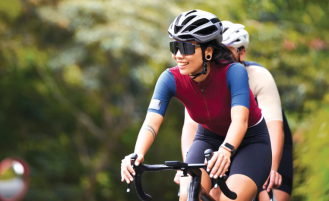 Woman rides bike in forested area.