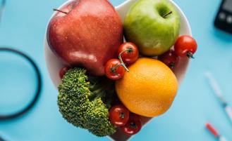 A bowl of fruit for a healthy diet with medical diabetes support devices in the background