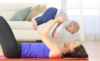 Mother holding baby on yoga mat