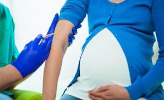 Pregnant person receiving a shot from a healthcare professional