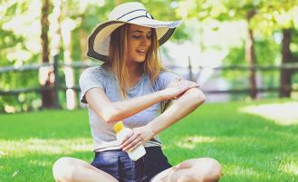 Person applying sunscreen in sun hat