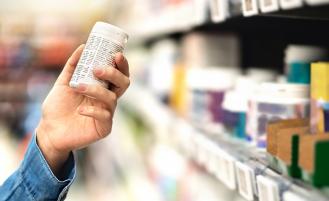 person-holding-medicine-bottle-next-to-shelf-in-store