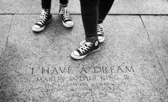 Close up of two individuals wearing Converse tennis shoes next to "I Have a Dream" plaque.