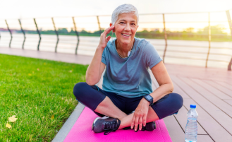 Older woman sits on pink yoga mat.