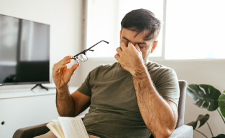 Man with headache takes off glasses and rubs his eyes.