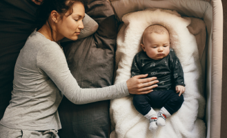 Baby sleeps in bassinet next to mother.